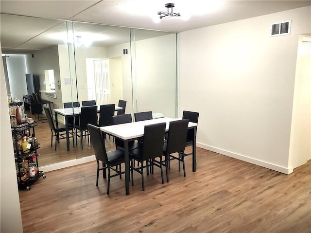 dining area with visible vents, baseboards, and wood finished floors