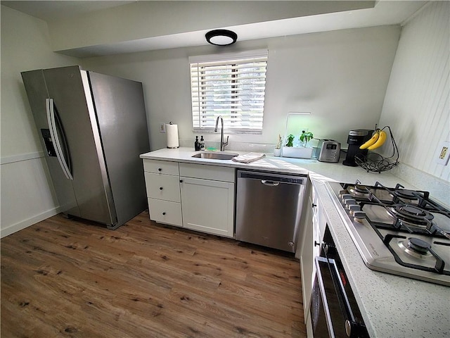 kitchen with a sink, light countertops, appliances with stainless steel finishes, and dark wood-style floors
