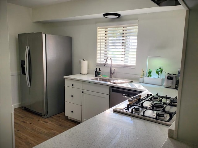 kitchen with white cabinetry, appliances with stainless steel finishes, wood finished floors, light countertops, and a sink