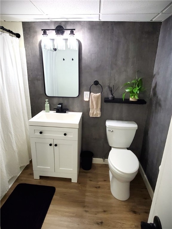 bathroom featuring walk in shower, a drop ceiling, toilet, wood-type flooring, and vanity