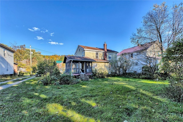 rear view of house featuring a lawn and a sunroom