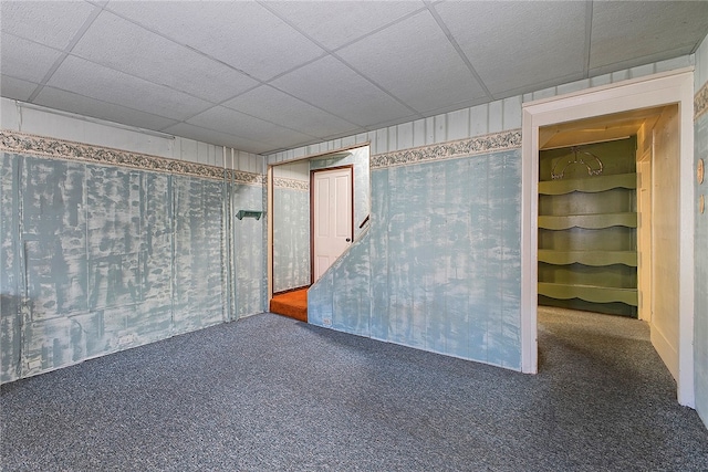 unfurnished room featuring a drop ceiling and dark colored carpet