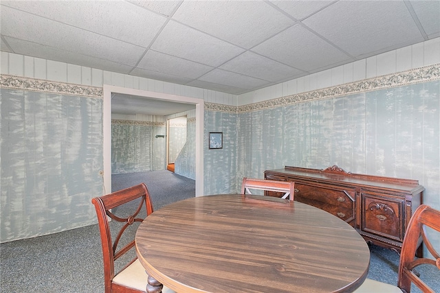 carpeted dining space with a paneled ceiling