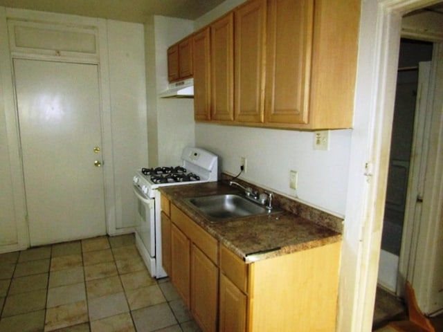kitchen with under cabinet range hood, brown cabinets, white gas range, a sink, and light tile patterned flooring