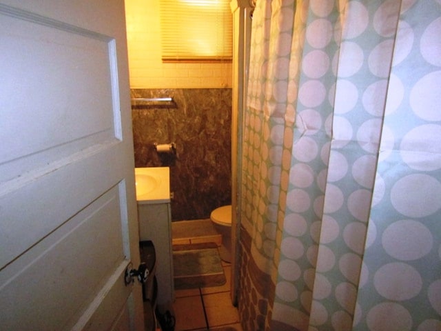 bathroom featuring toilet, tile patterned floors, tile walls, vanity, and a shower with curtain