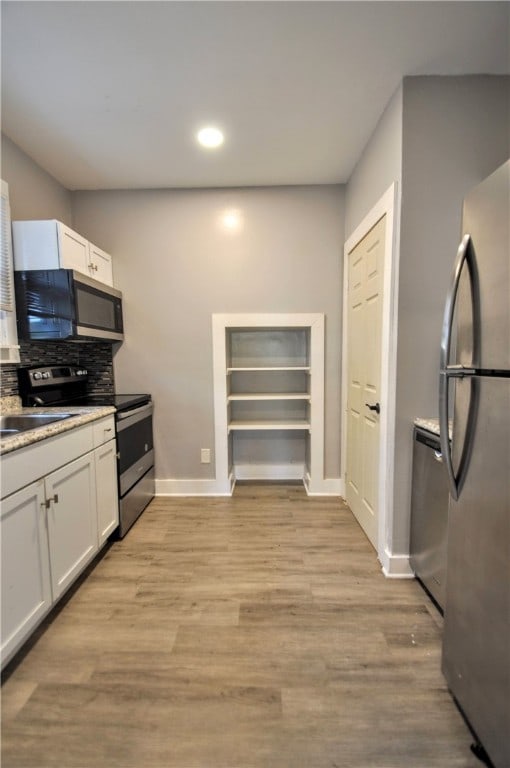 kitchen with stainless steel appliances, white cabinets, light hardwood / wood-style flooring, and sink