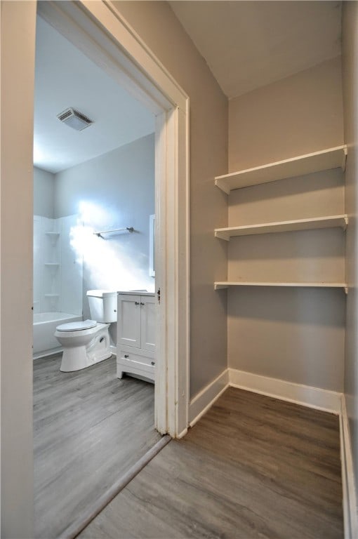 full bathroom featuring wood-type flooring, bathtub / shower combination, vanity, and toilet