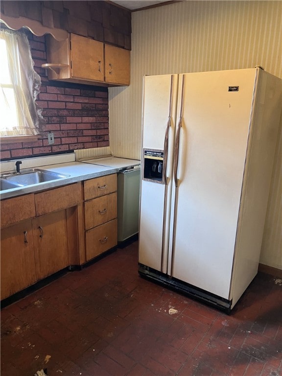 kitchen with stainless steel dishwasher, sink, and white refrigerator with ice dispenser