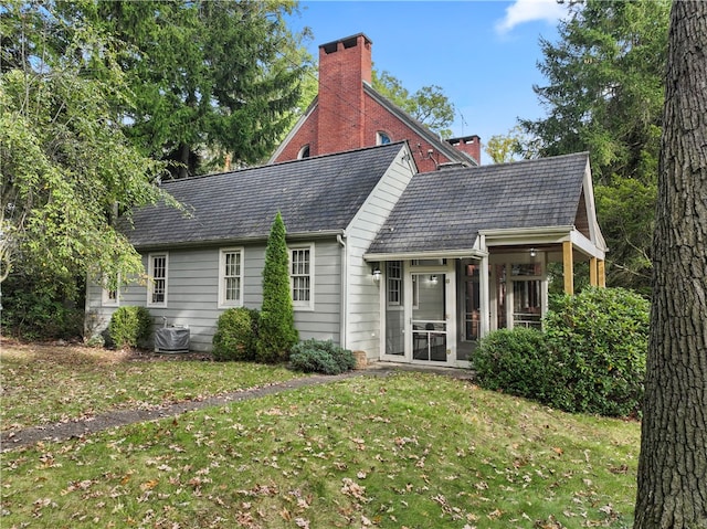 back of property featuring a sunroom, central AC unit, and a lawn