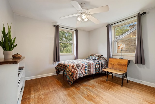 bedroom with light hardwood / wood-style floors, ceiling fan, and multiple windows