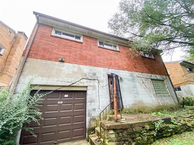 rear view of property featuring a garage and brick siding