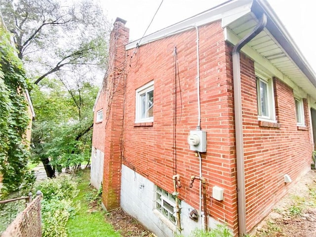 view of side of property featuring a chimney and brick siding