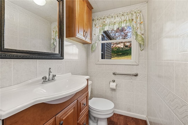 bathroom with hardwood / wood-style floors, toilet, tile walls, and vanity