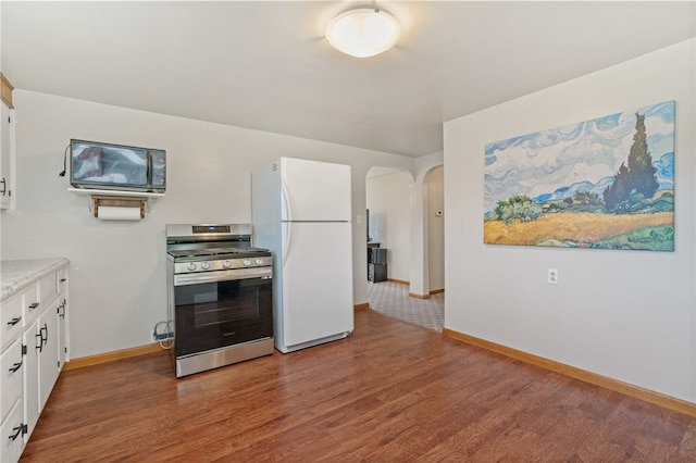 kitchen featuring stainless steel range, white refrigerator, white cabinetry, and dark hardwood / wood-style flooring