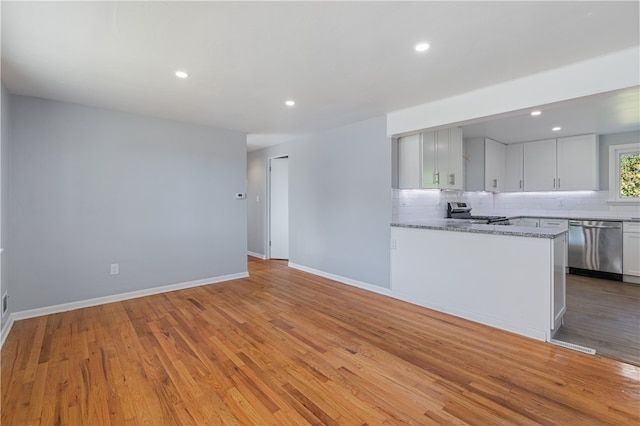 kitchen featuring light wood-type flooring, light stone countertops, stainless steel appliances, white cabinets, and kitchen peninsula