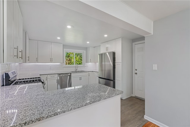 kitchen featuring light stone countertops, stainless steel appliances, kitchen peninsula, and white cabinetry