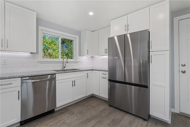 kitchen with sink, light stone counters, stainless steel appliances, hardwood / wood-style flooring, and white cabinetry