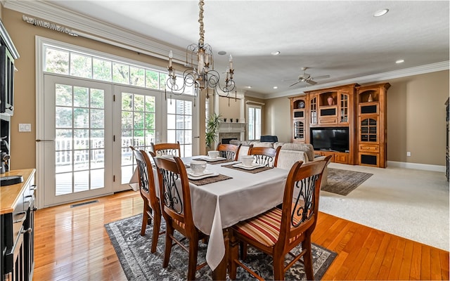 dining area featuring ornamental molding, light hardwood / wood-style floors, and ceiling fan with notable chandelier