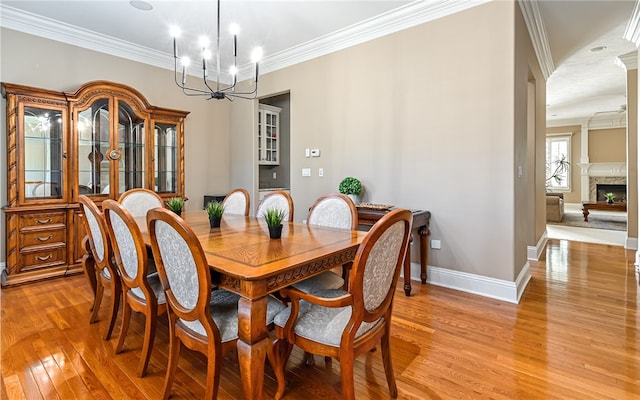 dining area with a notable chandelier, light hardwood / wood-style floors, and ornamental molding