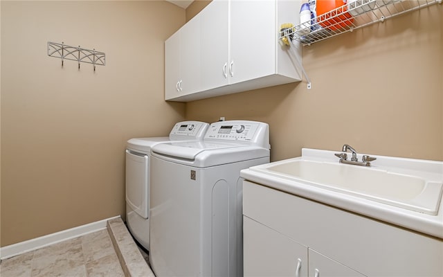 laundry room featuring washer and clothes dryer, sink, and cabinets