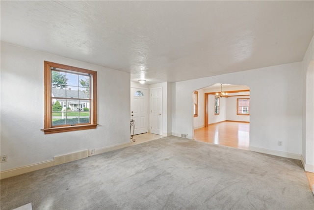 carpeted spare room featuring an inviting chandelier and a textured ceiling