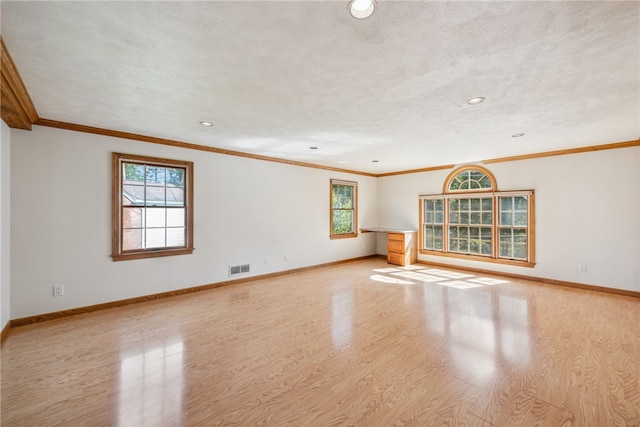 unfurnished living room featuring ornamental molding, light wood-type flooring, and plenty of natural light