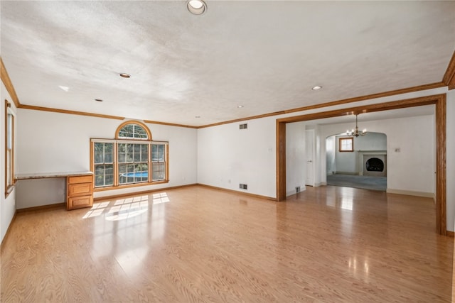 unfurnished living room featuring light wood-type flooring, crown molding, built in desk, and a chandelier