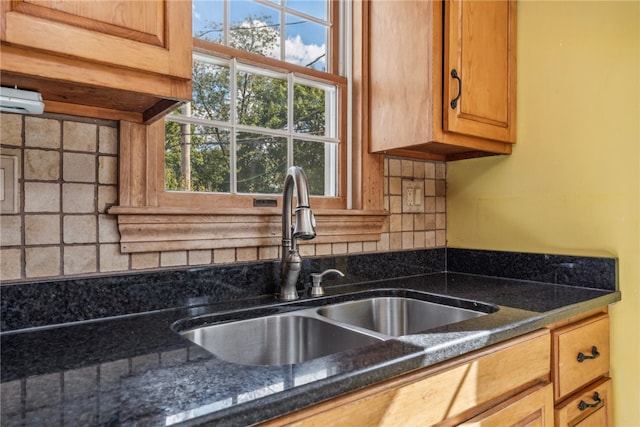 room details with dark stone countertops, decorative backsplash, and sink