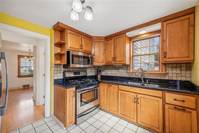 kitchen featuring backsplash, appliances with stainless steel finishes, a chandelier, and sink