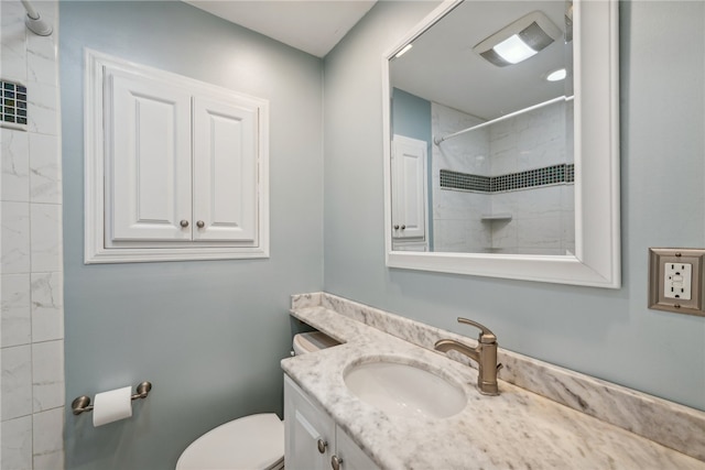 bathroom featuring a tile shower, toilet, and vanity