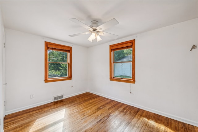 empty room featuring ceiling fan, plenty of natural light, and light hardwood / wood-style floors