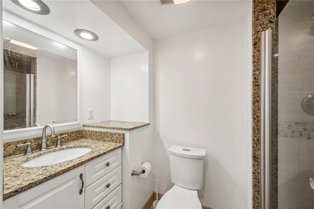 bathroom featuring vanity, walk in shower, and toilet