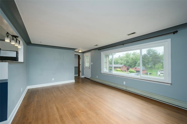 empty room with light hardwood / wood-style floors and baseboard heating