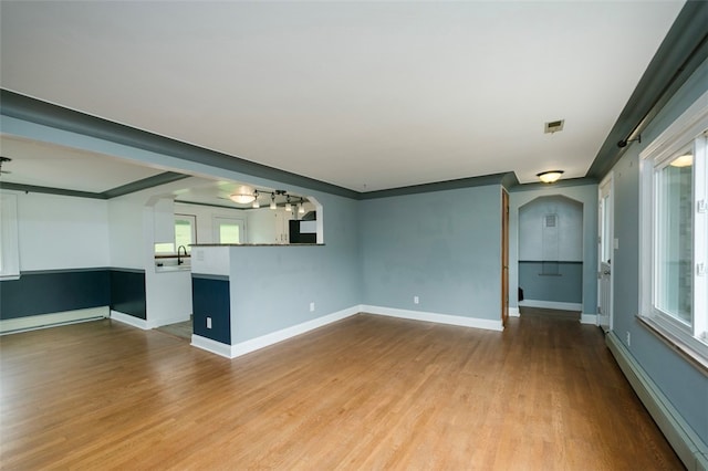 unfurnished living room featuring crown molding, a baseboard heating unit, sink, and light hardwood / wood-style flooring