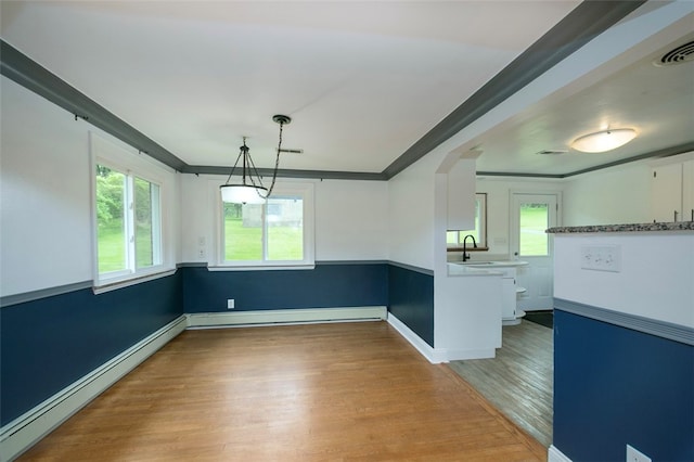 unfurnished dining area featuring ornamental molding, hardwood / wood-style floors, baseboard heating, and sink