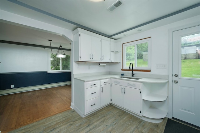 kitchen featuring sink, light hardwood / wood-style floors, white cabinetry, hanging light fixtures, and baseboard heating