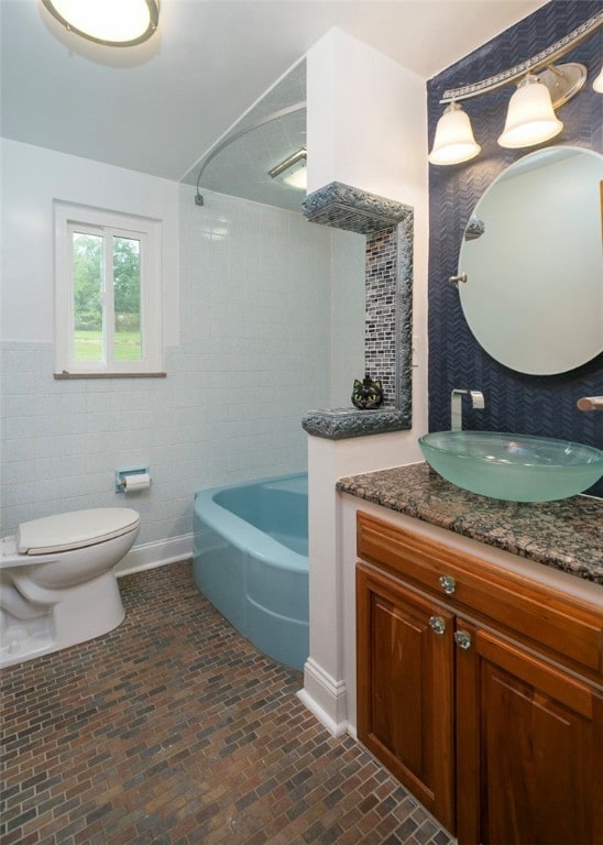 full bathroom featuring vanity, tile walls, toilet, and washtub / shower combination