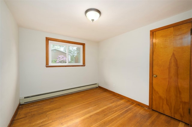 spare room with wood-type flooring and a baseboard radiator