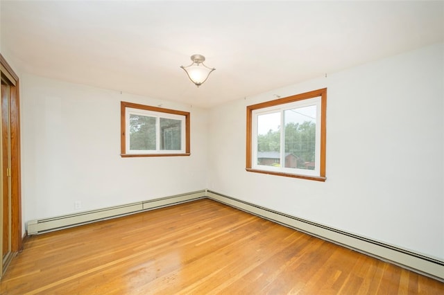 spare room with a baseboard heating unit and wood-type flooring