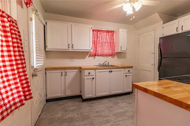 kitchen featuring ceiling fan, white cabinets, sink, black fridge, and butcher block countertops