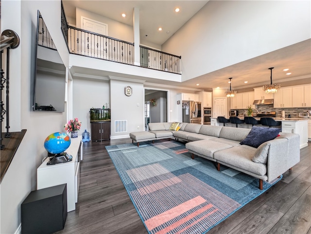 living room featuring an inviting chandelier, a high ceiling, and dark hardwood / wood-style flooring