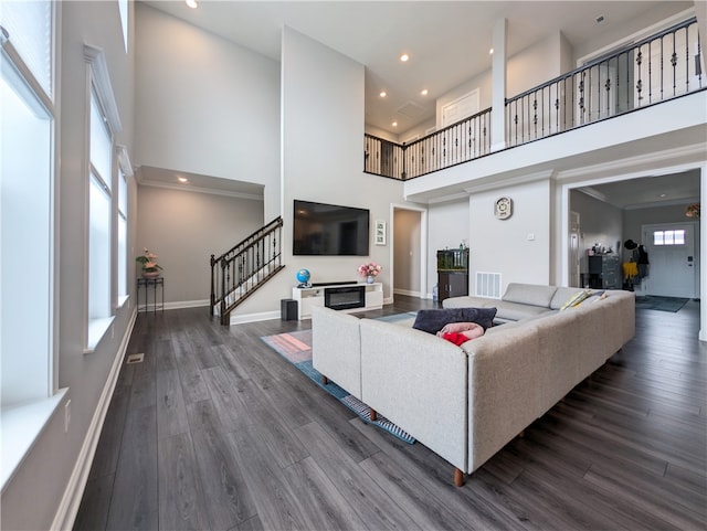 living room featuring a towering ceiling and dark wood-type flooring