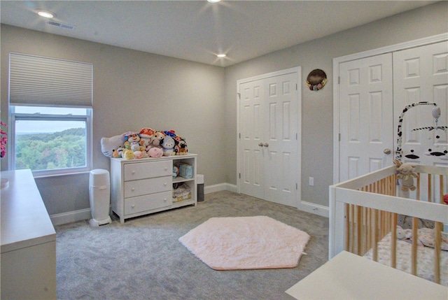 bedroom with light carpet, a nursery area, and a closet