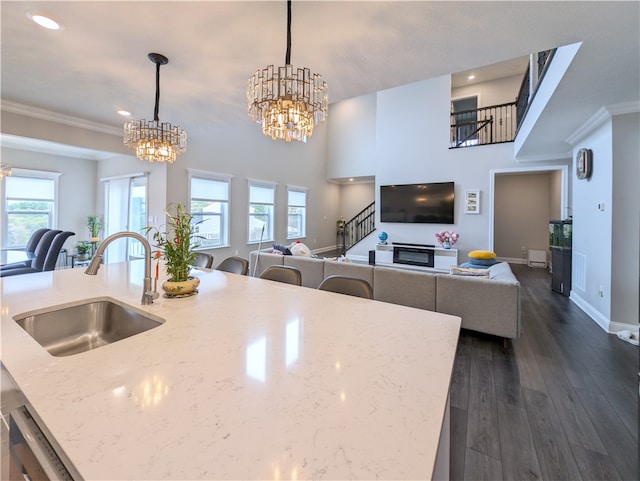 kitchen featuring light stone countertops, a kitchen island with sink, dark hardwood / wood-style floors, sink, and pendant lighting