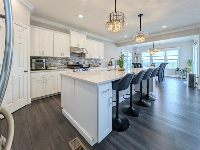 kitchen with a center island with sink, dark hardwood / wood-style flooring, hanging light fixtures, and white cabinets