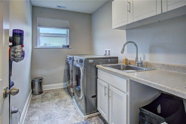 clothes washing area with cabinets, sink, and independent washer and dryer