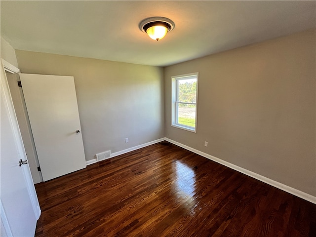 unfurnished room with dark hardwood / wood-style flooring