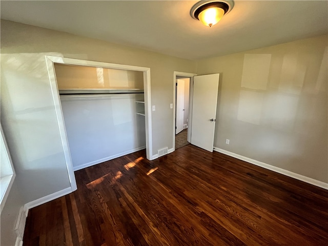 unfurnished bedroom featuring a closet and dark hardwood / wood-style flooring