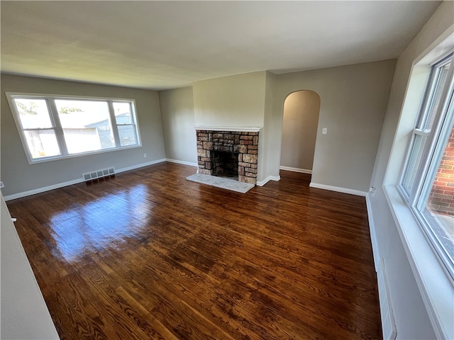 unfurnished living room with a stone fireplace and dark hardwood / wood-style floors