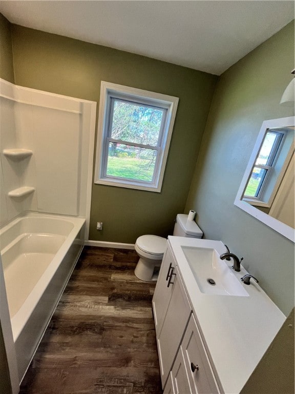 full bathroom with vanity, washtub / shower combination, hardwood / wood-style flooring, and toilet